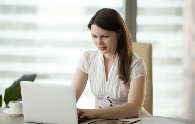 Frau arbeitet konzentriert am Laptop